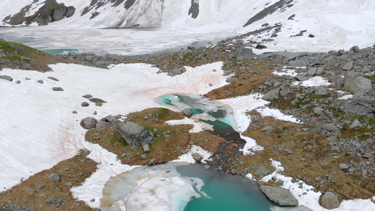 Luftfoto af frosne søer i de franske alper med sne, is og turkisblåt vand