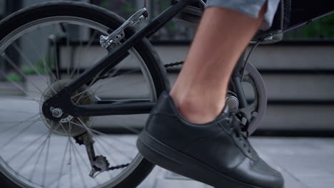 closeup male legs pedaling city street in black shoes. green transportation