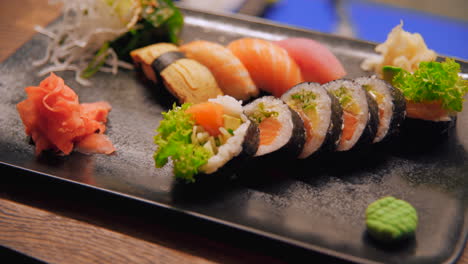 beautifully arranged sushi platter on a black plate featuring nigiri, salmon rolls, pickled ginger, wasabi, and fresh garnishes. a vibrant and appetizing japanese dish.