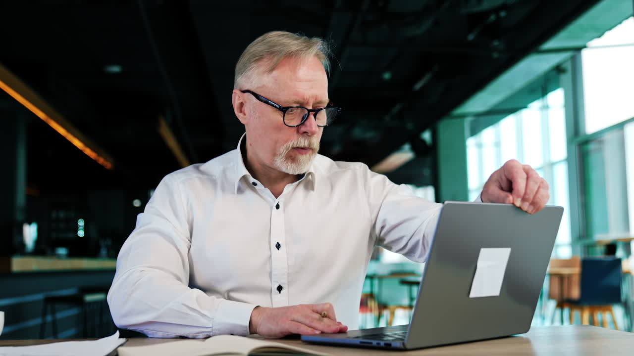 Focused busy man working in the office. Caucasian man opens laptop and reads information from the screen.