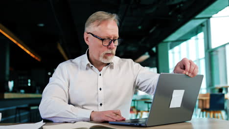 focused busy man working in the office. caucasian man opens laptop and reads information from the screen.