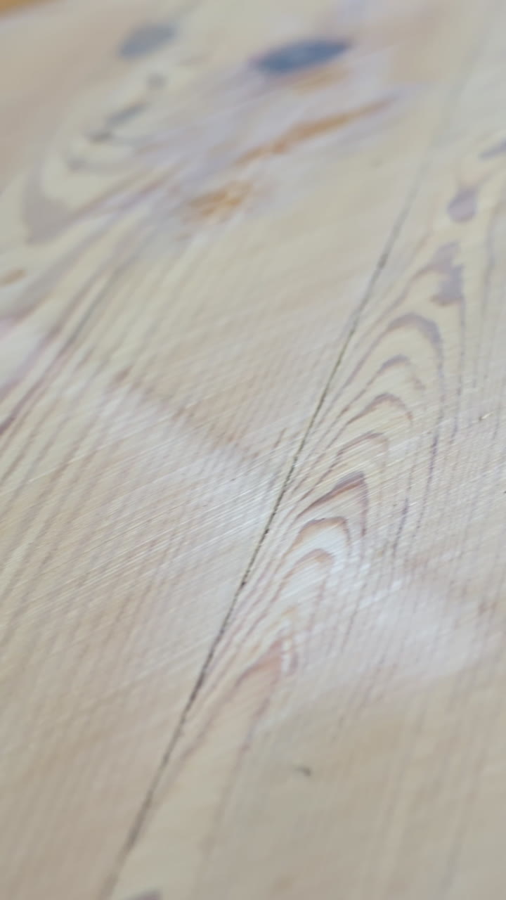 Detailed vertical shot captures the transition on pine wood floor as sanding removes the old finish, revealing natural grain and texture, highlighting restoration process and material details
