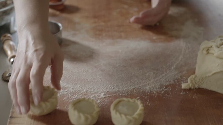Baking traditional Sardinian Panadas rolling dough with hands close