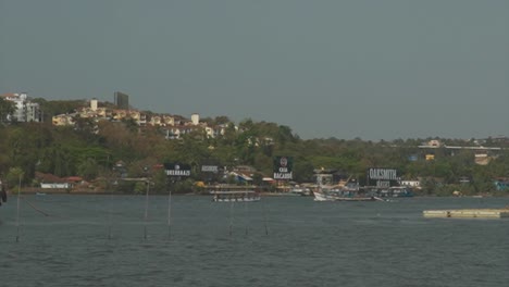 印度潘吉姆 (panjim) 的曼多維河 (mandovi river) 沿岸,一艘商用漁船 (commercial fishing boat) 沿著一艘運送一日遊客的渡輪 (ferry)