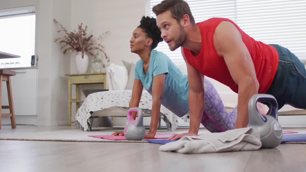 video de una pareja feliz y diversa entrenando juntos en casa, haciendo flexiones