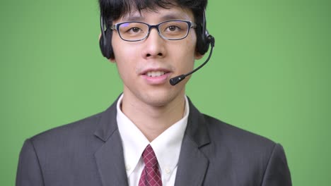 joven empresario asiático sonriendo y trabajando como representante de un centro de llamadas