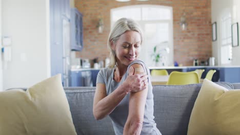 Portrait-of-happy-senior-caucasian-woman-in-living-room-with-bandage-on-her-arm