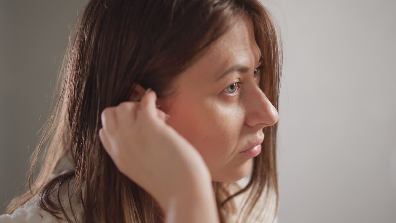 Woman wipes face with facial toner in toilet. Attractive brunette lady in plush robe applies moisturizing toner on face in bathroom slow motion