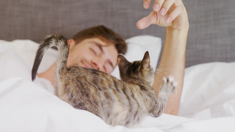 happy young man lying on bed playing with his tabby cat 4k 4k