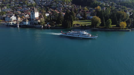 fantástica toma aérea de seguimiento de un barco de pasajeros y vista del castillo de oberhofen en suiza, en un día soleado