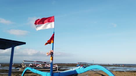 Die-Indonesische-Flagge-Weht-Am-Traditionellen-Segelboot-Sanur-Beach-Skyline-Von-Bali-Indonesien-über-Der-Blauen-Skyline-Und-Dem-Meer