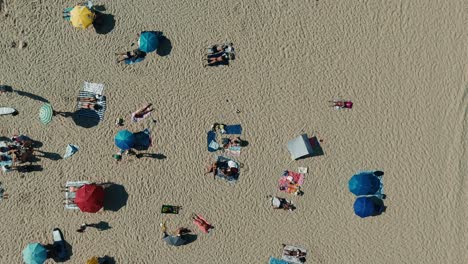 Aerial view of people relaxing on the beach with umbrellas