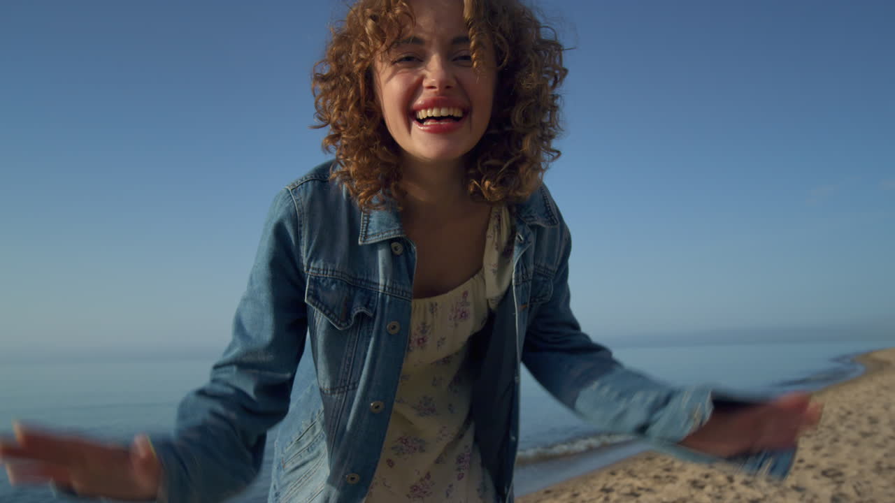 Smiling woman video chatting with friend on smartphone. Joyful girl waving hands