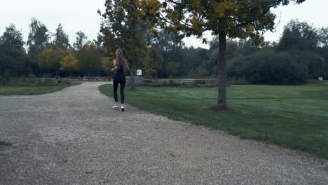 Toma-De-4k-De-Hermosas-Mujeres-Jóvenes-Corriendo-Y-Trotando-Al-Aire-Libre-En-Un-Parque-Al-Amanecer-Con-Cielo-Nublado