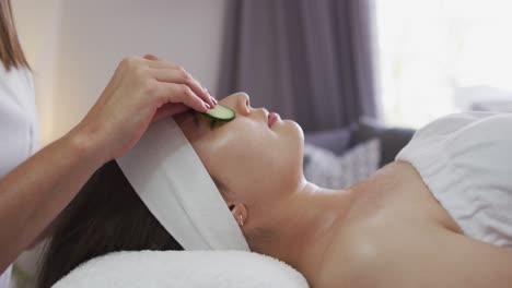 caucasian woman lying back while beautician gives her a facial