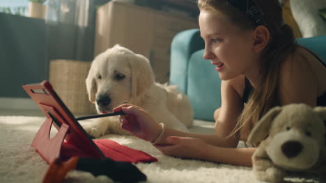 girl interacting with a puppy while using a tablet