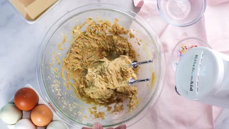 baking confetti sugar cookies and using a white electric mixer to combine the batter. in the kitchen making a dessert. making confetti sugar cookies with a white background, pink napkin and eggs