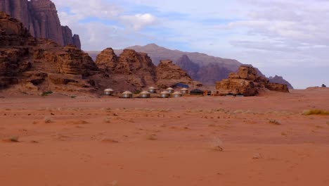 tiendas beduinas árabes anidadas contra las escarpadas montañas en el remoto desierto de wadi rum, jordania, oriente medio