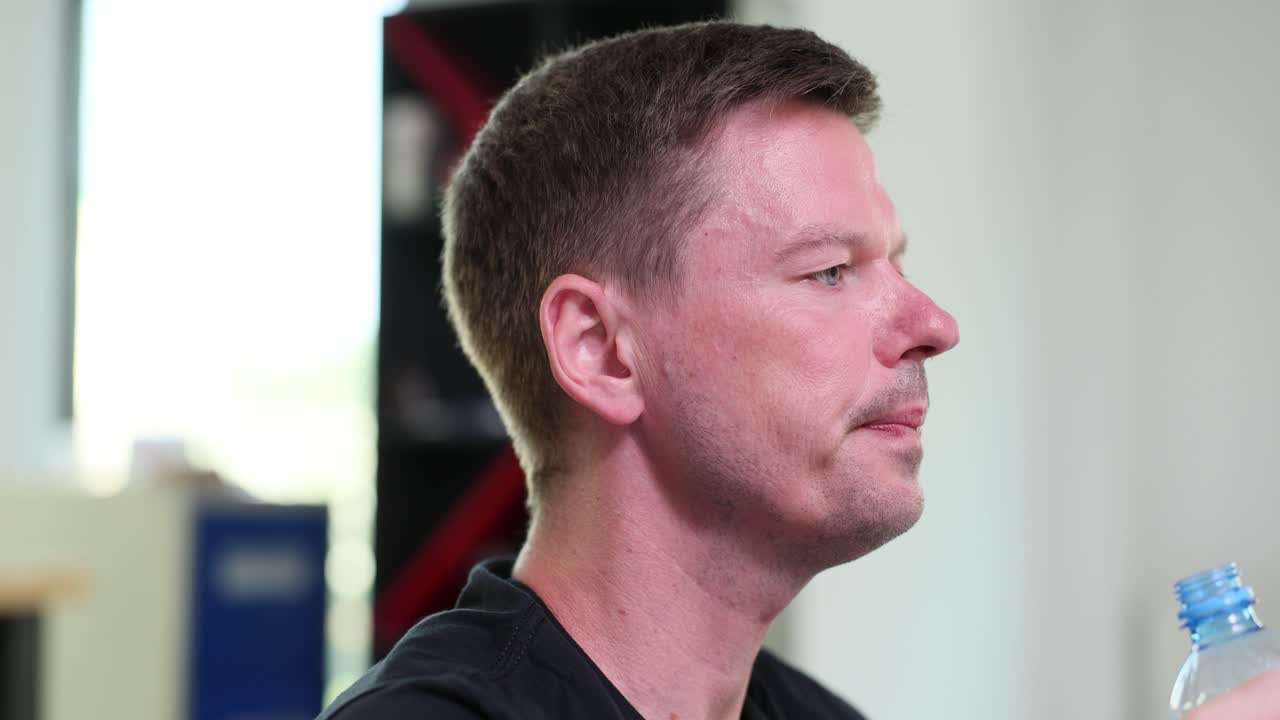 A man drinks water from a plastic bottle to hydrate