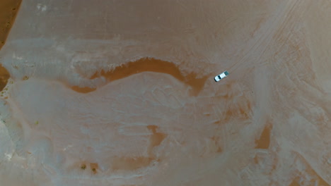 Aerial-top-down-of-AWD-Jeep-with-roof-tent-driving-through-the-dessert-near-Sossuvlei,-Sesriem-in-Namibia