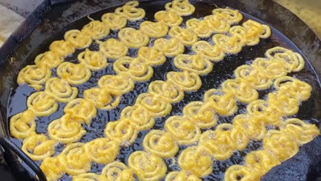 rows of jalebi being fried in large pan at chawk bazar in dhaka