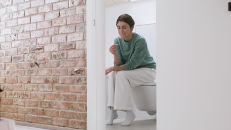 mujer con prueba de embarazo en el baño