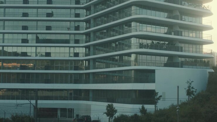 Edificio de la ciudad con cristal reflectante durante el atardecer cerca de las vías del tren, mostrando la vida urbana y
