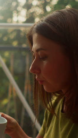 worried woman distracts from work for break to take sip of fresh tasty coffee. woman continues to hold cup in right hand gazing thoughtfully into middle