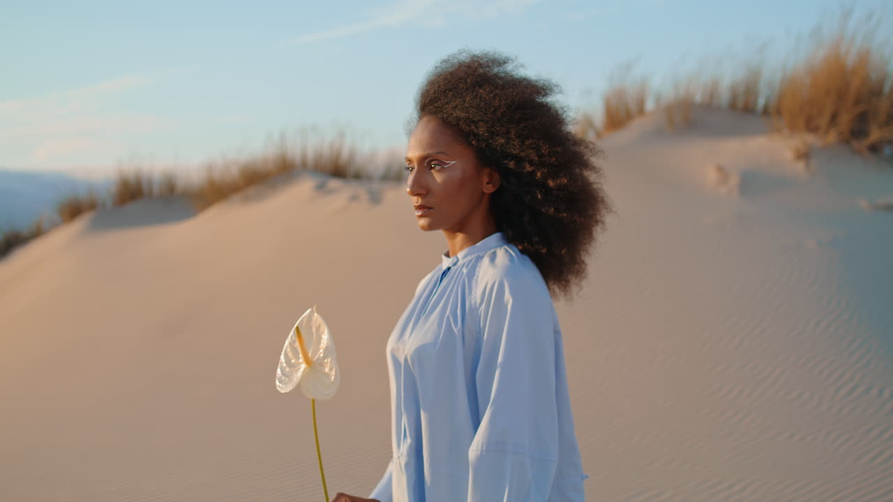 la cara de la chica de la portada de la flor de pie en el desierto closeup. mujer tranquila posando con calla