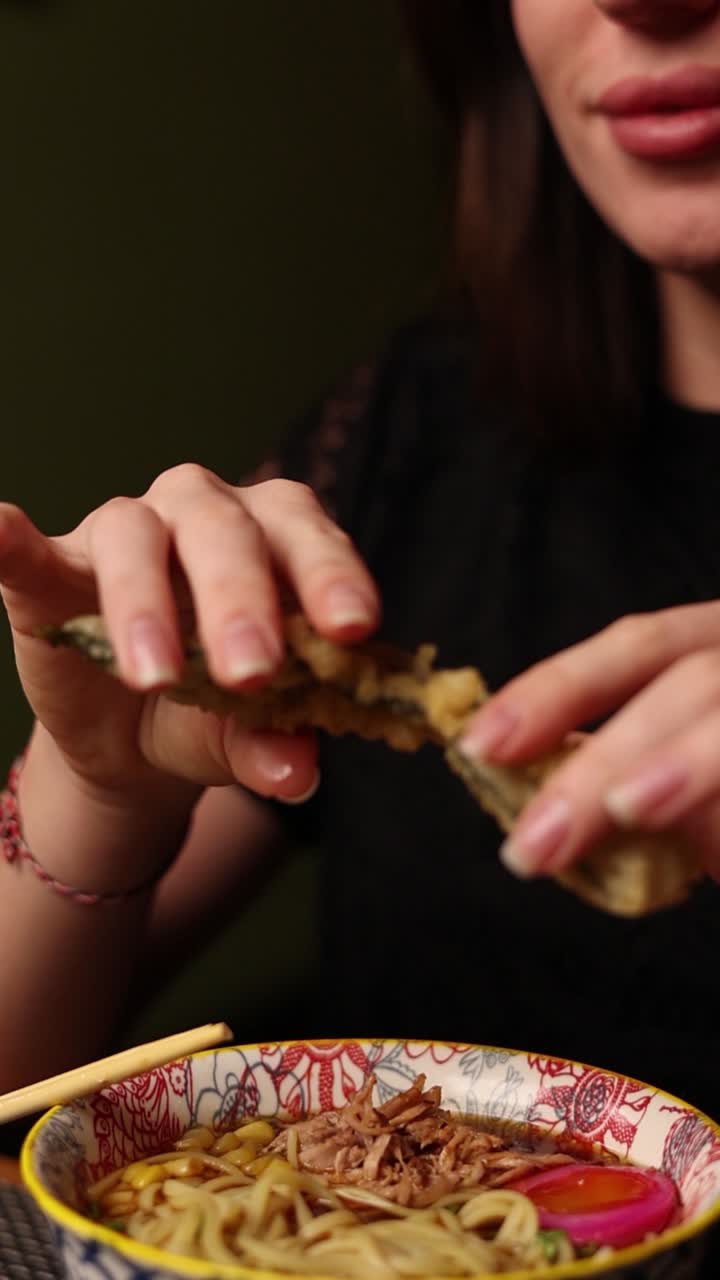 una mujer comiendo ramen con tempura.