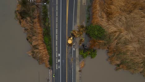 vista aérea de un tractor empujando la vegetación de la carretera