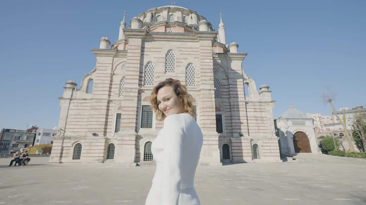 una mujer hermosa va a la mezquita. acción. vista trasera de una mujer hermosa caminando frente a la mesquita. una mujer atractiva entra en la mezquita en un día soleado en estambul