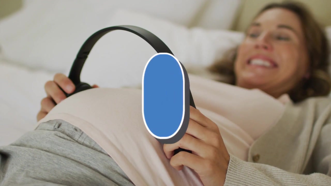 Vídeo vertical: Mulher grávida sorrindo deitada na cama com blusa rosa, ajustando fones de ouvido para verificar curtidas azuis.