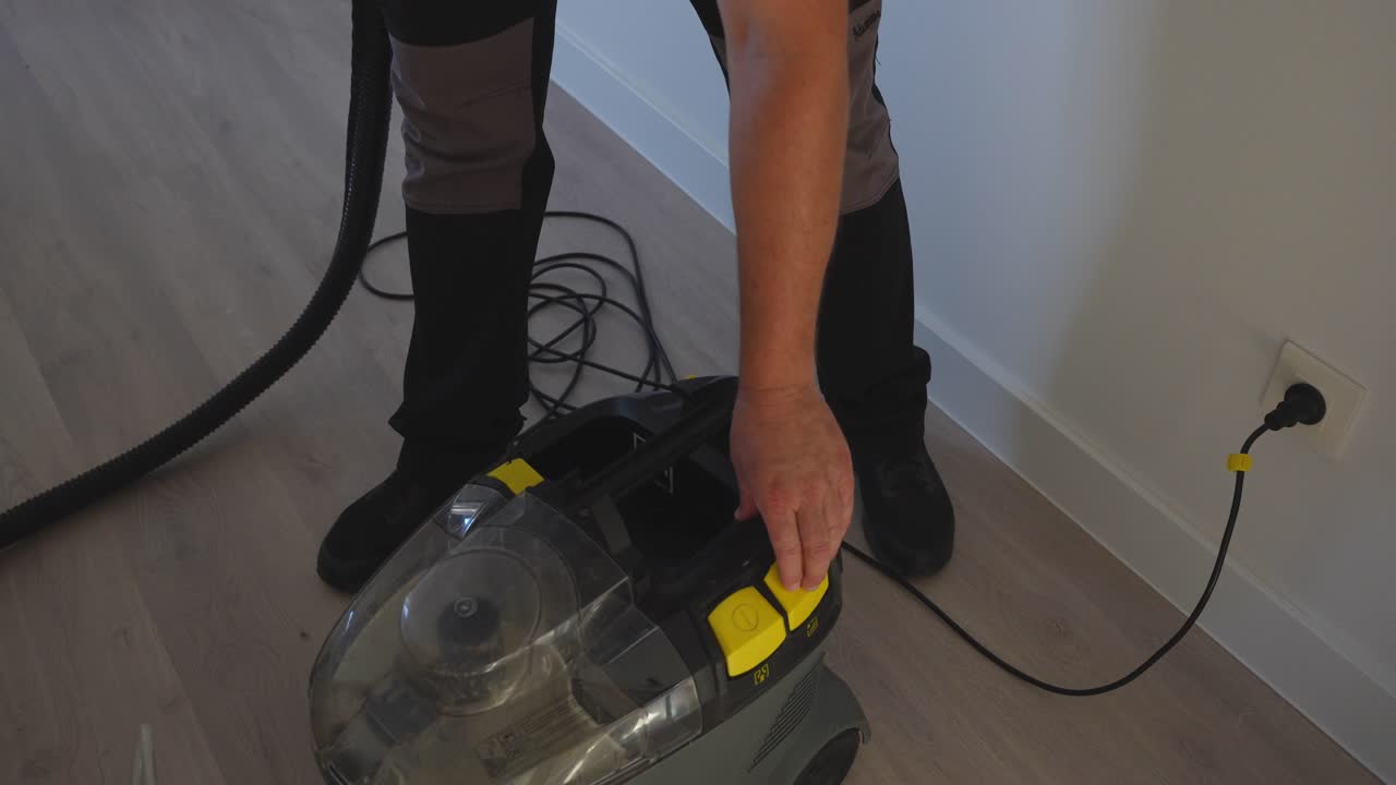Top down view of a man plugging in and turning on a pressure washer with ionized water inside to clean the sofa
