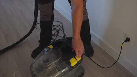 top down view of a man plugging in and turning on a pressure washer with ionized water inside to clean the sofa