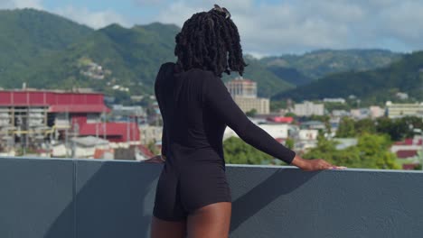 menina de cabelo natural olha para uma cidade caribenha cênica de port of spain de um telhado