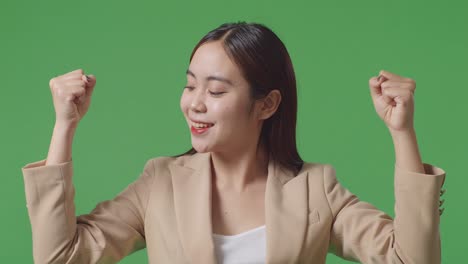 close up of asian business woman smile and flex muscle on green screen background in the studio