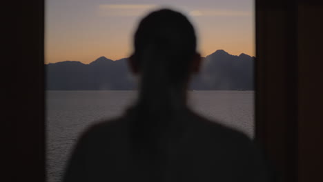 a woman in front of the window with a sea view