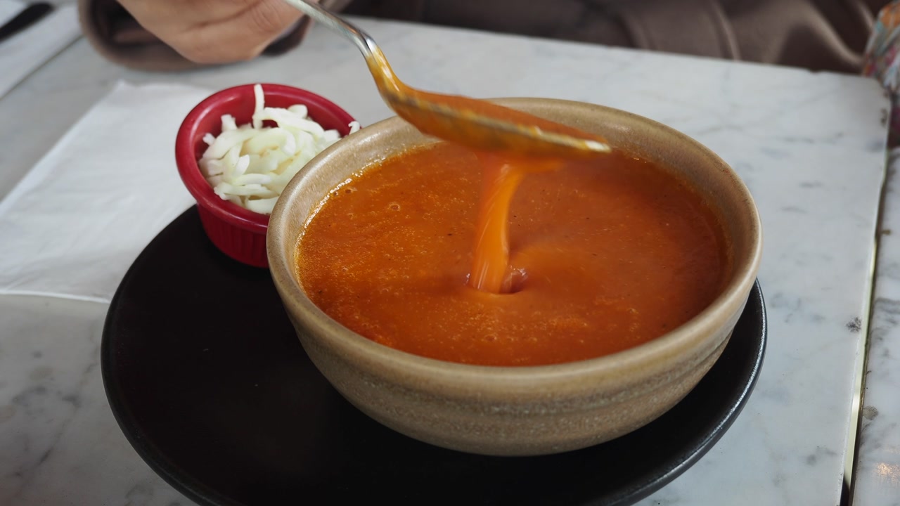 Creamy Tomato Soup Being Stirred and Served with Cheese