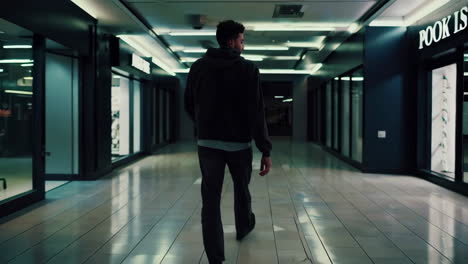man walking in an empty mall at night