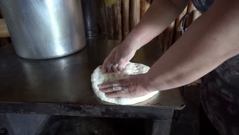 woman bare hands flatten bread dough on a traditional georgian oven, close up