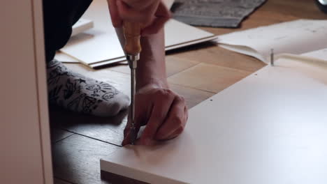 Primer-Plano-De-La-Mano-Masculina-Girando-Un-Tornillo-En-Un-Estante-De-Madera---Calcetines-Elegantes