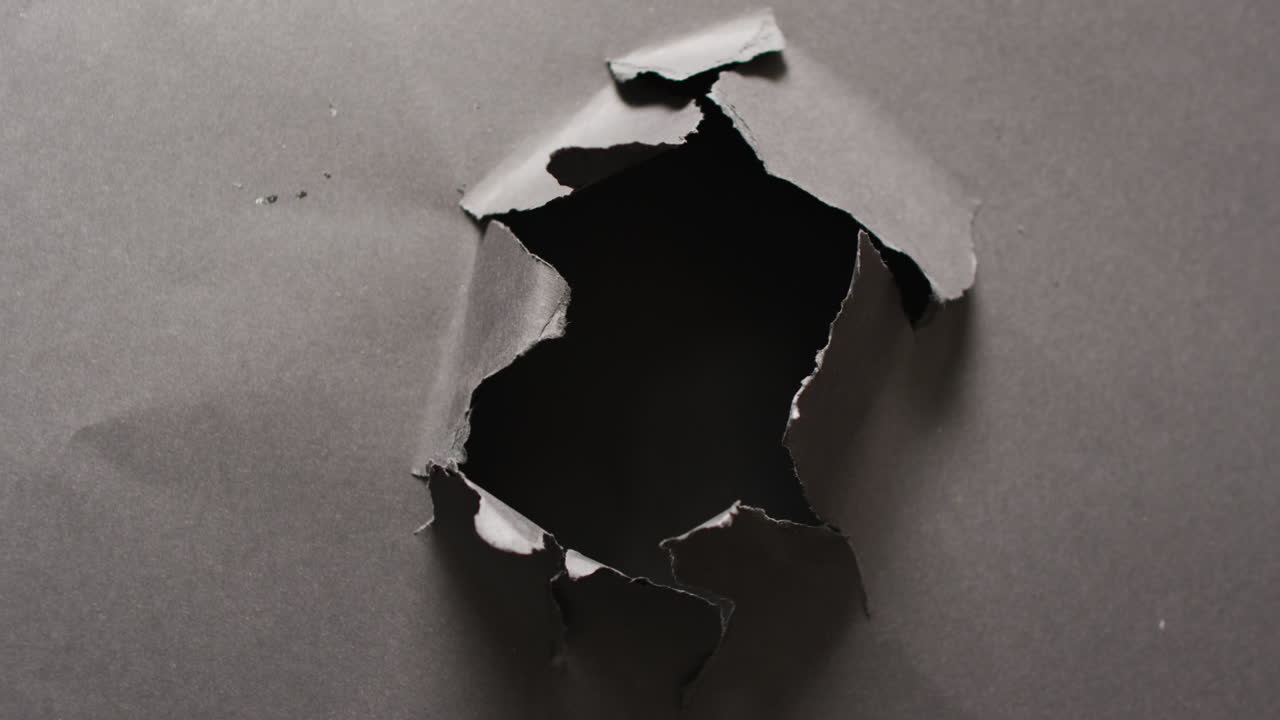 검은 바탕에 어진 회색 종이의 클로즈업 비디오