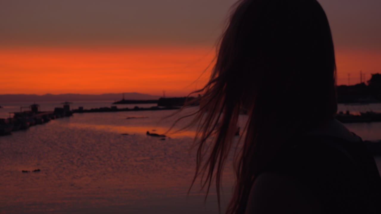 외로운 여자가 저녁에 작은 항구를 쳐다보고 있습니다.