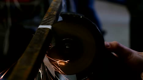 worker cuts a metal bar of angular grinding machine, closeup