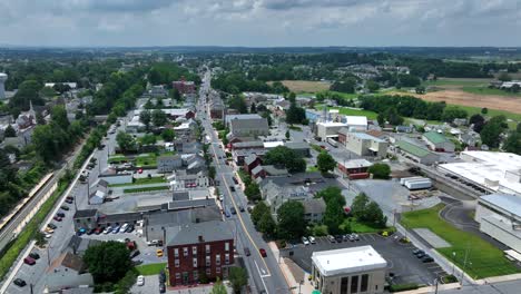 traffic on main street of historic american town. cloudy and sunny day in summer. industrial factory behind houses and homes. aerial rising wide shot