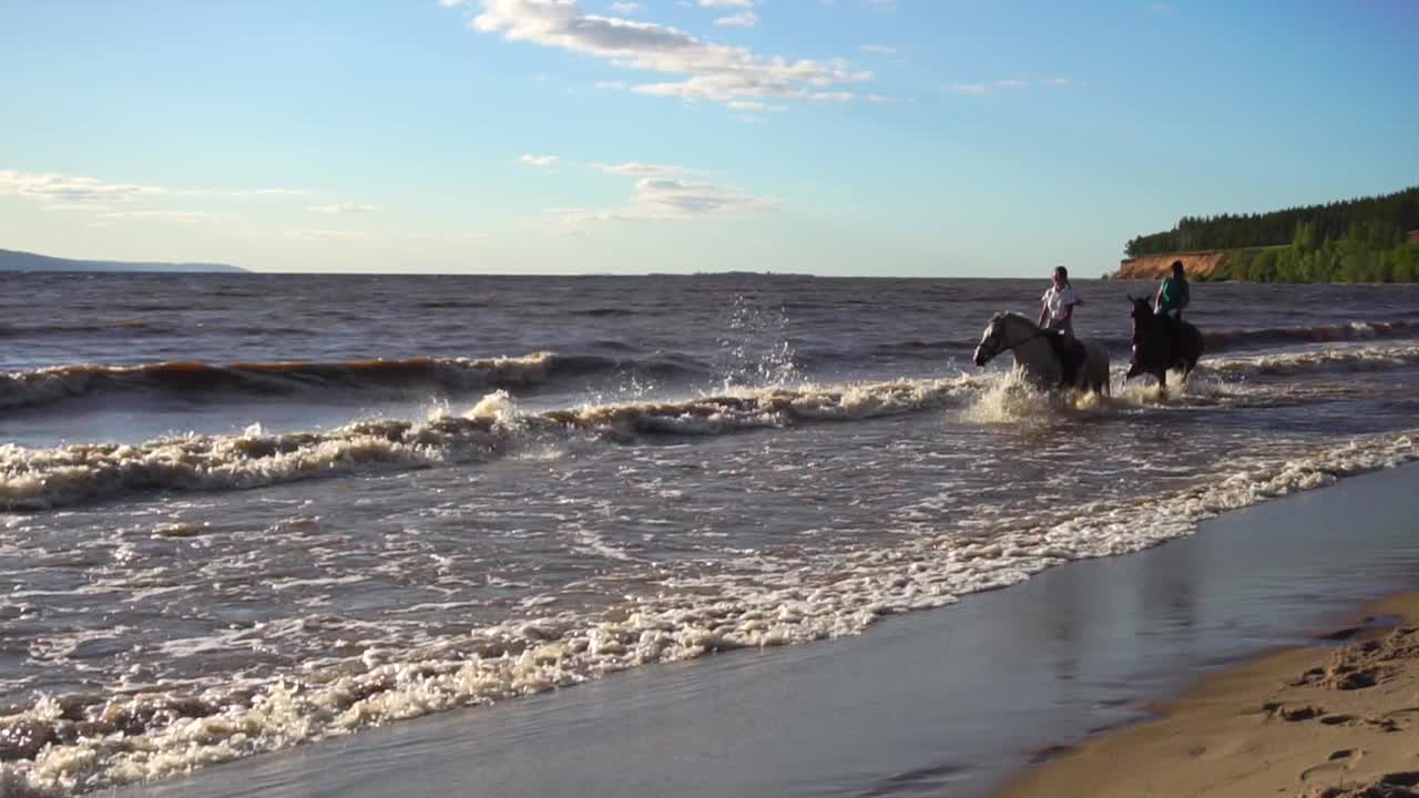 Persone a cavallo tra le onde sulla spiaggia