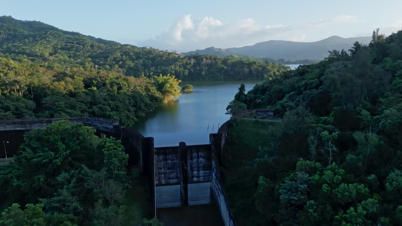 Aerial approaching shot of Hatillo Dam with picturesque seascape landscape of Dominican Republic. Tranquil and peaceful scenery with mountains at sunset. Wide shot.