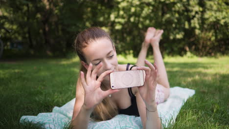 Schöne-Kaukasische-Frau,-Die-Auf-Einer-Wiese-Liegt-Und-Ein-Foto-Mit-Ihrem-Smartphone-Macht