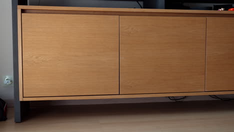 large wooden nightstand standing in the room. door of the furniture opens and little toddler boy peeps out of it